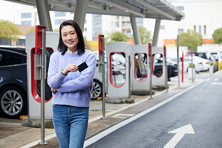 女性站在充电桩旁边展示卡片图片