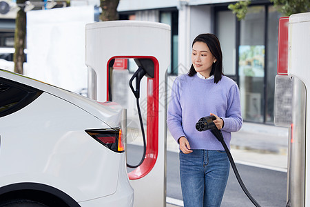 环保汽车海报休闲女性给新能源汽车充电背景