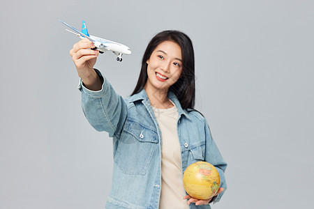 护照年轻女性手拿地球仪和飞机模型背景