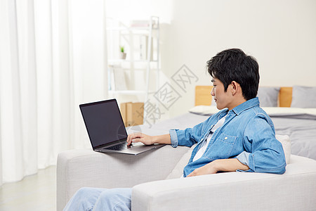男青年沙发上使用电脑和手机图片
