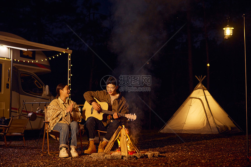 年轻夫妻户外露营夜晚篝火弹琴图片