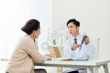 患者交流医生给中年女性患者讲解x光片背景