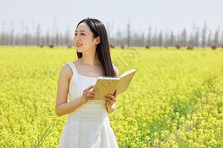 在油菜花海看书的女性图片