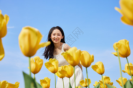 微笑美女清新夏日蓝天郁金香花海的少女背景