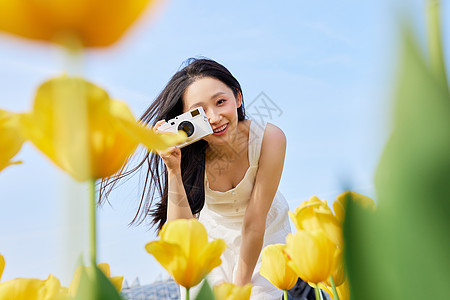 女性春游郁金香前景手拿照相机的美女背景