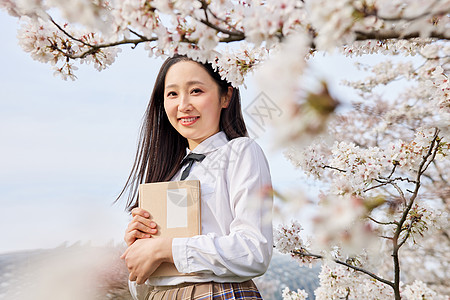 樱花树下年轻女性看书图片