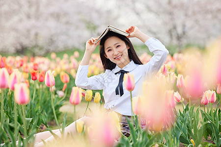 手绘少女坐在郁金香花海里看书的制服女性背景