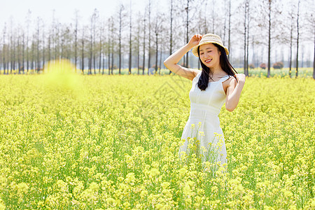 少女站在油菜花田里享受阳光图片