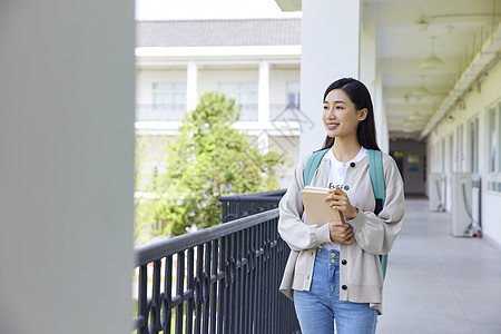 气质美女校园里手拿书本的女大学生背景