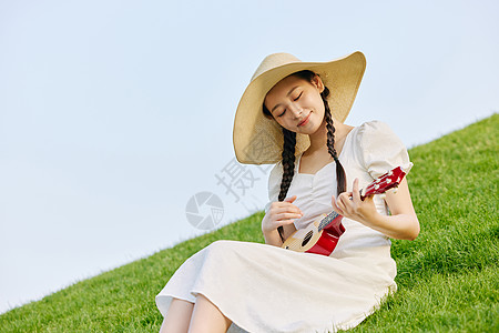 阳光和女生草坪上的文艺女性弹尤克里里背景