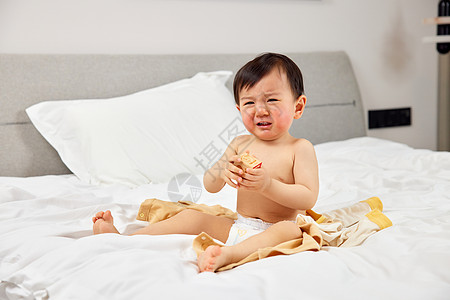 哭和笑坐在床上哭闹的婴儿宝宝背景