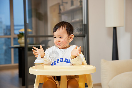 坐在宝宝椅上开心微笑的婴幼儿背景图片