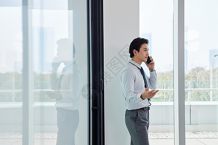 站在窗边打电话的商务男性图片