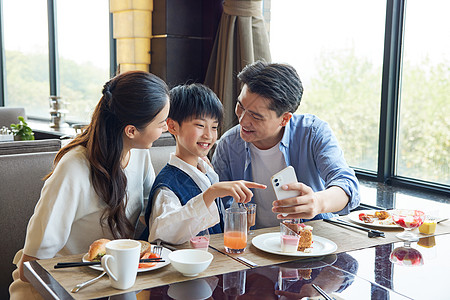 温暖的家庭餐桌上聚餐餐厅桌上看手机的一家人背景