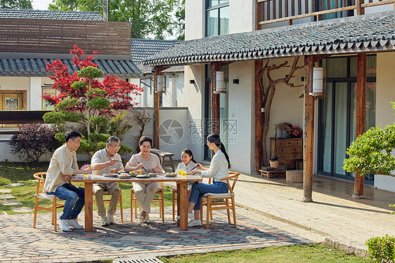 一家五口坐在院子里开心用餐图片