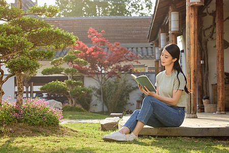 幸福快乐坐在院子里看书阅读的女性背景