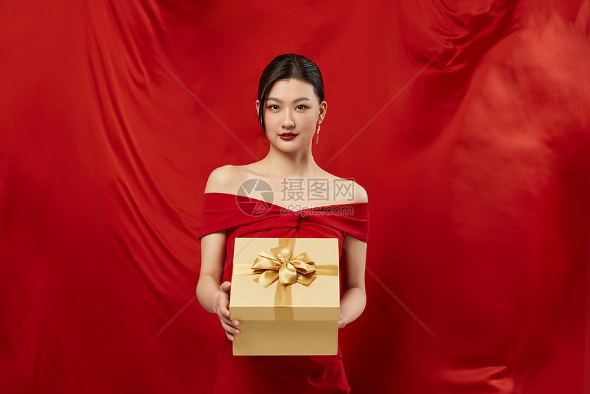 红色背景手拿礼盒的性感女性图片
