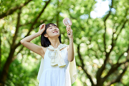 户外使用便携风扇的少女图片