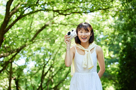 青春少女手拿照相机户外散步图片