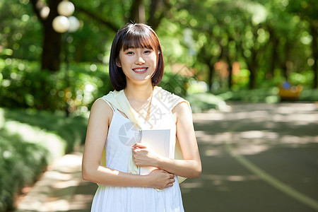 森系少女室外女生抱着书本散步背景