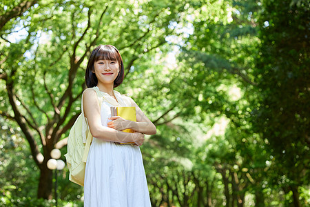 绿色长裙美女室外女生拿着书本散步背景