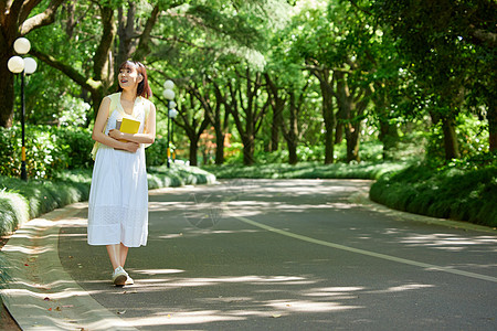 可爱玉米室外女生抱着书本散步背景