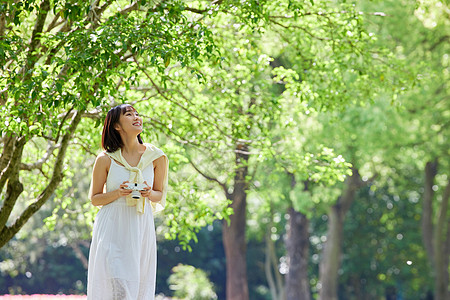 手拿照相机在公园散步的女孩背景图片