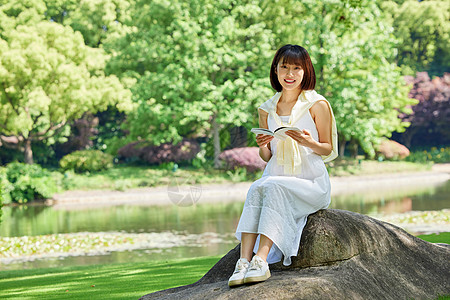 活力学生女生夏日坐在河边石头上看书形象背景