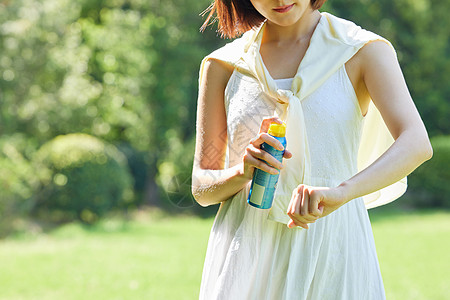 女性夏日防晒女性室外使用防晒喷雾特写背景