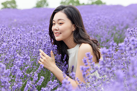 夏日风景蹲下闻薰衣草的女性背景