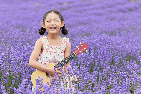 小女孩站在薰衣草花海里弹奏尤克里里图片