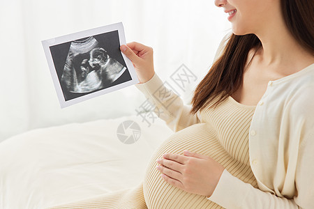 怀孕准妈妈手拿b超图特写背景图片