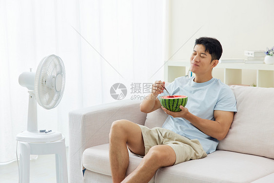 夏日享受西瓜风扇的男人图片