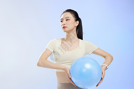 运动少女佩戴电子手表锻炼瑜伽球图片