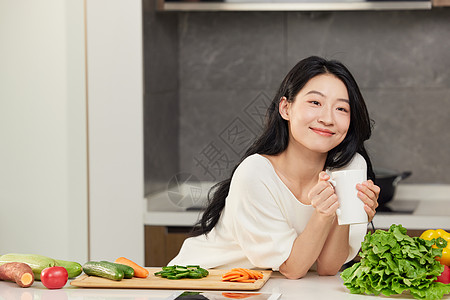 女性手捧饮品靠在餐桌边形象图片