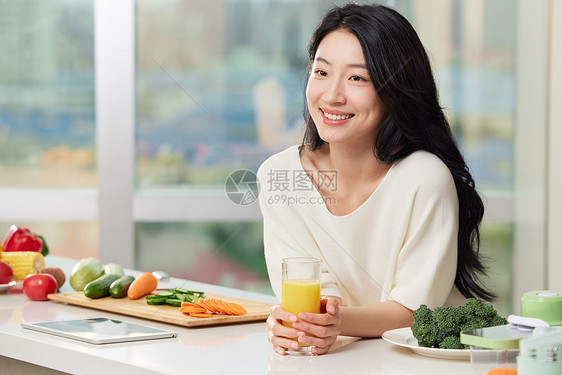 女性手捧橙汁在餐桌边形象图片