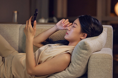 手机用素材躺在沙发上玩手机眼睛不适的女性形象背景