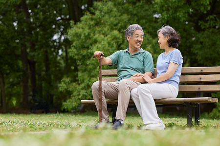 白发夫妻老年人坐在公园长椅上聊天背景