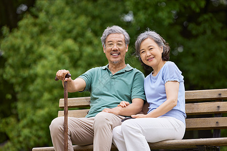 白发夫妻老年人坐在公园长椅上聊天背景