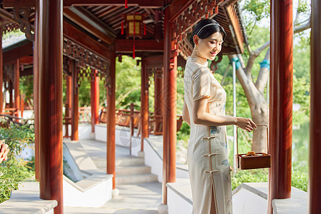 手拿点心盒走在中式庭院的旗袍美女图片