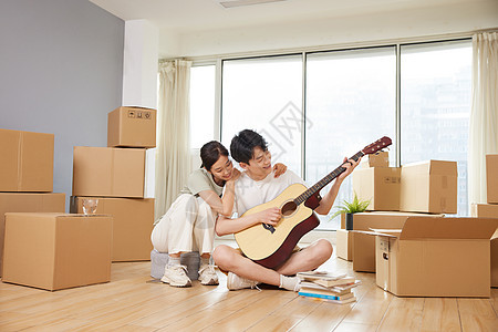 在新家地板上弹奏吉他的夫妻形象图片