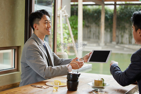 在湖边茶桌前谈生意的白领图片