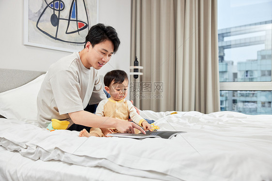 卧室里年轻父亲陪宝宝玩耍图片