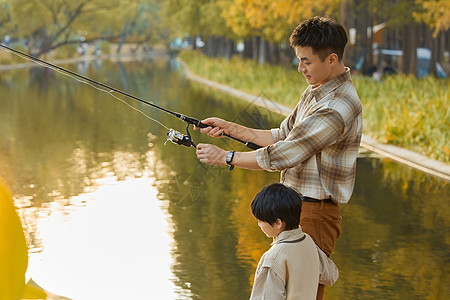 男孩在河边观察父亲钓鱼背景图片