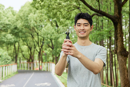 青年户外手拿拍摄设备的男性形象背景