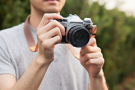 男性户外使用照相机拍照图片