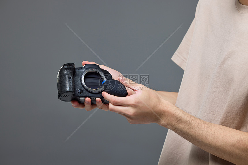 摄影师使用气吹给照相机清灰尘特写图片