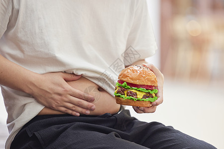 肥胖的人手拿汉堡摸肚子图片