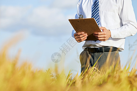 拿着记录板视察农田的科研人员特写图片