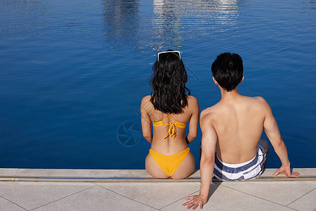 身材完美的情侣坐在泳池边背影图片